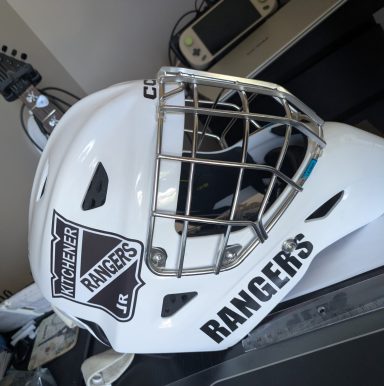 White goalie hockey helmet with a Kitchener Jr. Rangers logo and a metal cage.