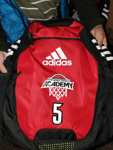 Red Adidas backpack with "ACADEMY" and the number "5" displayed prominently.