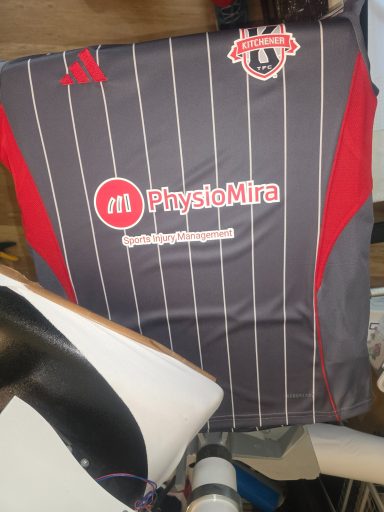 Gray and red soccer jersey with vertical stripes and a logo on the front.