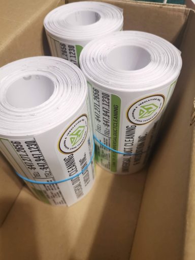 Three rolls of printed labels in a cardboard box.